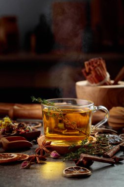 Mutfak masasında malzemeler ve baharatlar olan bir fincan bitki çayı..