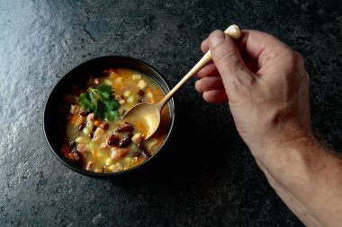 Siyah taş bir masada patates, domates, paprika, havuç ve pastırma ile kırmızı fasulye çorbası. Üst Manzara. Boşluğu kopyala.