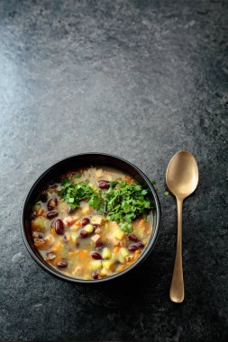 Siyah taş bir masada patates, domates, paprika, havuç ve pastırma ile kırmızı fasulye çorbası. Üst Manzara. Boşluğu kopyala.