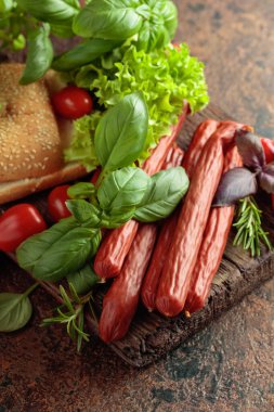 İnce tütsülenmiş sosisler, eski bir kesim tahtasının üzerinde ekmek ve yeşillikler..