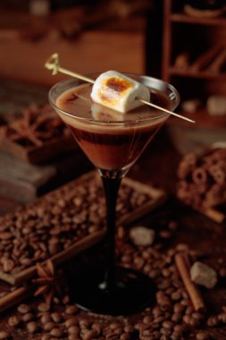 Krema ve kahve kokteyli, kızarmış marşmelovla süslenmiş. Karışık malzeme ve baharatlarla dolu bir masada kahve içeceğiz..