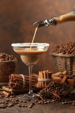 Çikolatalı martini kokteyli ya da İrlanda kremalı likörü şişeden bardağa doldurulur. Kahve çekirdekleri, tarçın çubukları ve anason masaya saçılmış..