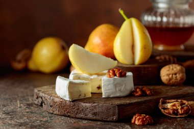 Kahverengi bir masada armutlu, cevizli ve ballı Camembert peyniri..