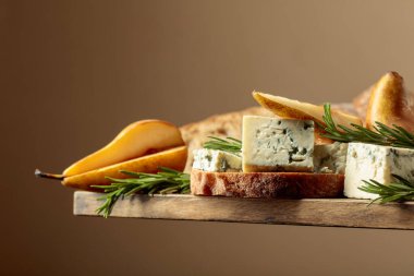 Mavi peynirli, armutlu ve biberiyeli sandviç. Eski ahşap bir masada ciabatta, mavi peynir, armut ve biberiye.