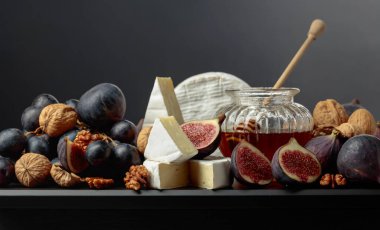 Siyah arka planda meyveli yumuşak peynir. İncirli, üzümlü, cevizli ve ballı Camembert peyniri..