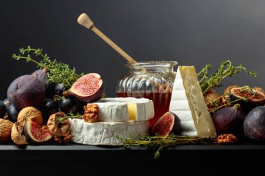 Siyah arka planda meyveli yumuşak peynirler. İncirli, üzümlü, cevizli, ballı ve kekikli Camembert peyniri..