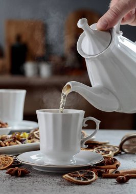 Eski bir taş masanın üzerinde malzemelerle birlikte bitki çayı. Bitki çayı bir fincana doldurulur..