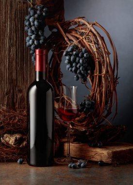 Bir şişe porto şarabı eski bir tahtanın, kurutulmuş asmanın ve mavi üzümün arka planına karşı. Yıllanmış şarap konsepti.