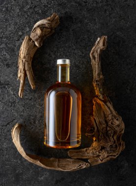 Bir şişe viski ve siyah taşlı arka planda eski pürüzler. Üst görünüm.