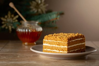 Noel ağacının arka planında katmanlı ballı kek. Geleneksel Noel pastası. Boşluğu kopyala.