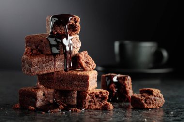 Siyah arka planda brownie parçaları. Browninin içine erimiş çikolata damlıyor. Boşluğu kopyala.