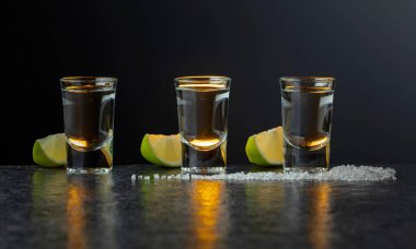 Taş bir masada limonlu ve tuzlu Meksika tekilası. Kopyalama alanı olan koyu arkaplan.
