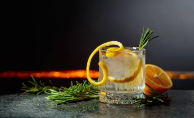 Siyah arka planda limon ve biberiyeli cin tonik kokteyli. Boşluğu kopyala.