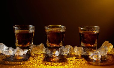 Viski şişeden cama doluyor. Viski ve buz siyah bir masada. Sarı ışık güzel gölgeler yaratır. Boşluğu kopyala.