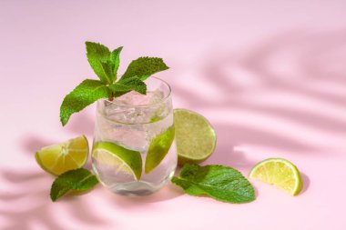 Buzlu, limonlu ve naneli yaz ferahlatıcı içecek. Kopyalamak için pembe arkaplan.