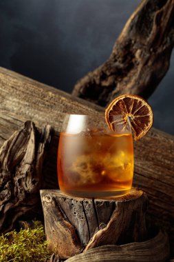 Eski moda bir karışım, buz ve kurutulmuş portakal dilimi ile eski ahşap bir kütükte..