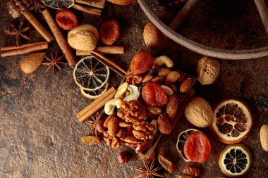 Kahverengi bir arka planda kurumuş meyve ve fındık. Kurutulmuş turunçgiller, kayısılar, kuru üzümler, çeşitli fındıklar ve baharatlar. Üst görünüm.