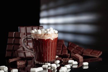 Cam bardakta mini marşmelovlu sıcak çikolata. Kırık bir arka planda acı çikolata.