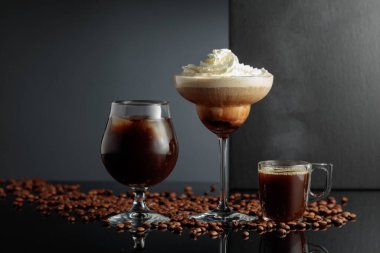 Siyah yansıtıcı arka planda koyu kahve ve buzlu kahve kokteylleri. Boşluğu kopyala.