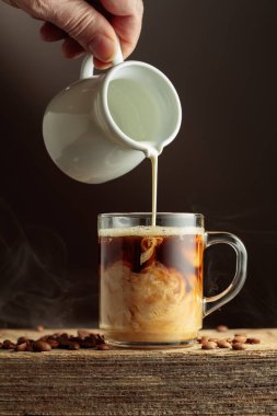 Sütlü cam bardakta bir kahve. Eski ahşap bir masada kahve. Boşluğu kopyala.