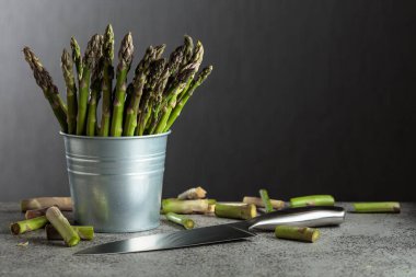 Gri arka planda küçük kovada taze kuşkonmaz. Boşluğu kopyala.