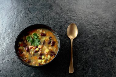 Siyah taş bir masada patates, domates, paprika, havuç ve pastırma ile kırmızı fasulye çorbası. Üst Manzara. Boşluğu kopyala.