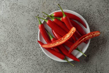 Gri taş bir masada yeşil saplı taze kırmızı biber. Üst görünüm, alanı kopyala.