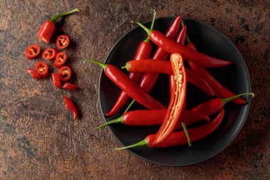 Kahverengi bir arka planda yeşil saplı taze kırmızı biber. Üst görünüm, alanı kopyala.