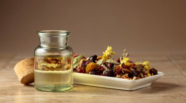 Temel yağ ya da küçük bir cam şişedeki bitkisel tentür. Bej bir arka planda kurutulmuş sağlıklı şifalı bitkiler ve şifalı bitkilerin karışımı. Boşluğu kopyala.