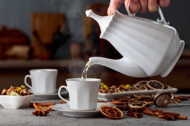 Eski bir taş masanın üzerinde malzemelerle birlikte bitki çayı. Bitki çayı bir fincana doldurulur..