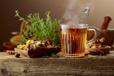 Çeşitli kurutulmuş malzemelerle birlikte bitki çayı ve eski ahşap bir masada taze kekik..