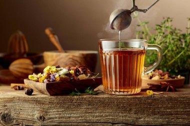 Çeşitli kurutulmuş malzemelerle birlikte bitki çayı ve eski ahşap bir masada taze kekik..