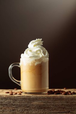 Krem şantili cam bardakta kahve. Eski ahşap bir masada kahve. Boşluğu kopyala.