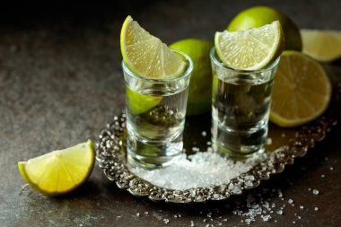 Gümüş tepside tuz ve limon dilimli tekila. Eski bir taş masada tekila..