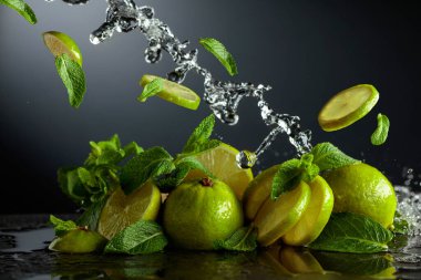 Siyah arka planda limon ve taze nane dalları. Serinletici içecekler ve su sıçraması için gerekli malzemeler. Boşluğu kopyala.