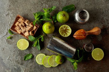 Tahta narenciye sıkacağı, karıştırıcı ve yaz ferahlatıcı içecekler yapmak için malzemeler. Esmer şeker, limon ve taş bir masada taze nane dalları..