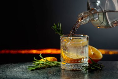 Limon ve biberiyeli cin tonik kokteyli. İçki şişeden buzlu bir bardağa dökülür. Boşluğu kopyala.