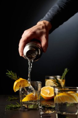 Limonlu ve biberiyeli kokteyl Cin ve Tonik. Barmen bardaktan bardağa kokteyl doldurur..