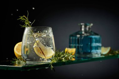 Limon ve biberiyeli cin tonik kokteyli. Limon dilimi bardağa dökülür Kokteylle.