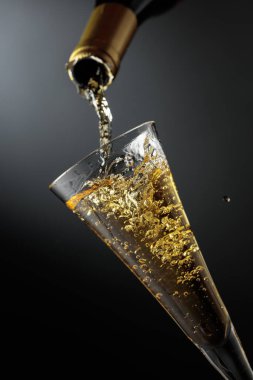 Beyaz köpüklü şarap şişeden bardağa dökülür. Detaylı bir yakın plan, şarabın hızlı akışını, doğal sıçramalar, damlalar ve kabarcıklar yarattığını gösteriyor. Kısa süreli bir çekim hareketi dondurur..