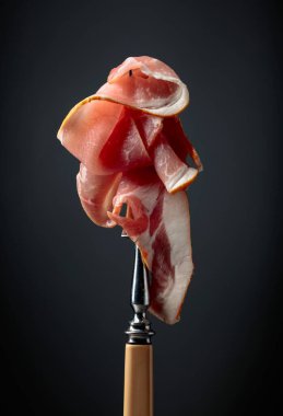 Çiğ taze domuz pastırması ve çatal. Siyah arka planda İngiliz pastırması.