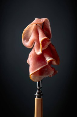 Çiğ taze domuz pastırması ve çatal. Siyah arka planda İngiliz pastırması.