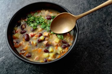 Siyah taş bir masada patates, domates, paprika, havuç ve pastırma ile kırmızı fasulye çorbası. Üst Manzara. Boşluğu kopyala.