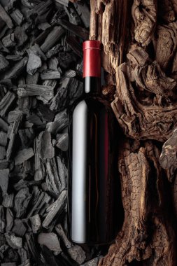 Bir şişe kırmızı şarap kömür ve kuru kaplara karşı. Zengin ve doymuş dokuları olan kavramsal bir görüntü..