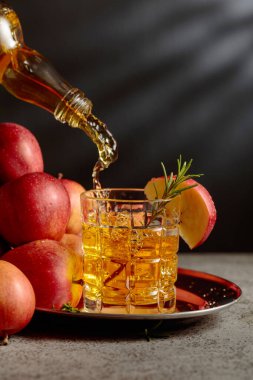 Elma şarabı şişeden bardağa dökülür. Eski bir mutfak masasında elmalı taze içecek. Boşluğu kopyala.