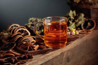 Eski ahşap bir masanın üzerinde çeşitli kurutulmuş malzemelerle birlikte bitki çayı. Boşluğu kopyala.