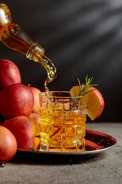 Elma şarabı şişeden bardağa dökülür. Eski bir mutfak masasında elmalı taze içecek. Boşluğu kopyala.