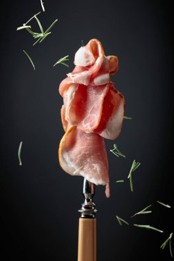 Çiğ taze domuz pastırması ve çatal. Siyah arka planda İngiliz pastırması.