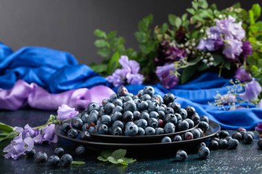 Siyah tabakta taze, sulu yaban mersini. Yaz aylarında yaban mersinleri, renkli bezelyeler ve çayır otlarıyla geçer..