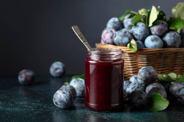 Lacivert arka planda erik reçeli ve taze böğürtlen. Mutfak masasında reçelli olgun erikler..